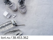 Здоровый образ жизни и фитнес в спорте, утренняя пробежка. Кроссовки, умный фитнес-трекер, беспроводные наушники и бутылка с водой на сером фоне. Вид сверху и плоское расположение. Стоковое фото, фотограф Photojuli / Фотобанк Лори
