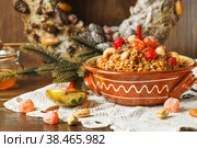 kutya, porridge with honey, nuts and berries, a traditional treat on Christmas Eve. Close-up, with a fir wreath in the background. Стоковое фото, фотограф Bogdanova Mariia / Фотобанк Лори