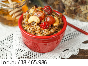 spelt porridge with nuts, honey and candied fruits. In a small red bowl on a linen napkin with embroidery. lean, vegetarian dish. Стоковое фото, фотограф Bogdanova Mariia / Фотобанк Лори