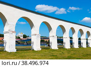 Аркада Гостиного двора и вид на Новгородский детинец (Новгородский кремль) и реку Волхов в летний солнечный день. Великий Новгород. Россия (2022 год). Редакционное фото, фотограф E. O. / Фотобанк Лори