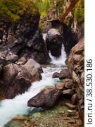 Waterfall on a mountain river. There is a suspension bridge for tourists. Стоковое фото, фотограф Виктория Тельминова / Фотобанк Лори