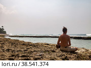 Rear view young man drummer, playing rhythm with djembe drum, sitting on tropical coral reef coast at ocean background. Travel vacation and music relaxation concept. Selective focus. Copy text space. Стоковое фото, фотограф Aleksandr Golubev / Фотобанк Лори