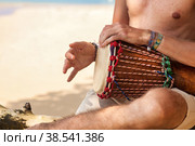 Close up hands young man drummer, playing rhythm on djembe drum on tropical sandy beach at sand background. Travel vacation and music relaxation concept. Selective focus. Copy text space. Стоковое фото, фотограф Aleksandr Golubev / Фотобанк Лори