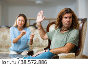 Portrait of frustrated man in room, while disgruntled wife scolds his. Стоковое фото, фотограф Яков Филимонов / Фотобанк Лори