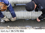 Emergency water service team cuts wraps the pipe with pieces of roofing felt and fixes them with stainless steel wire for waterproofing and heat insulation. reportage photography, Russia (2016 год). Редакционное фото, фотограф Olga Ovchinnikova / Фотобанк Лори