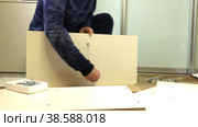 Wooden modular rack. Assembling a modular rack. A man connects the panels with a euro screw. Стоковое видео, видеограф Vadzim Yakubovich / Фотобанк Лори