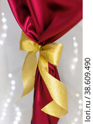 Golden bow on red cloth on a white background. Стоковое фото, фотограф Aleksandra Selivanova / Фотобанк Лори