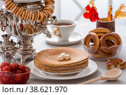 Русские традиции. Русский праздник Масленица. Натюрморт с чашкой чая, стопкой блинов, сметаной, медом, кубиками сливочного масла, рогаликами, вареньем из яблок, леденцом петушок и самоварами. Стоковое фото, фотограф Photojuli / Фотобанк Лори