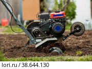 Banner. A male farmer plows the land with a cultivator. Agricultural machinery for tillage in the garden, combine harvester. Стоковое фото, фотограф Photojuli / Фотобанк Лори