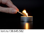 Крупный план женской руки, зажигающей свечу темной ночью дома. Стоковое фото, фотограф Васильева Юлия / Фотобанк Лори