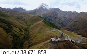 Aerial around view of ancient Gergeti Trinity church Tsminda Sameba, near mount Kazbek, a landmark of Georgia, Caucasus mountains. Стоковое видео, видеограф Поскребышев Михаил / Фотобанк Лори