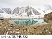 Beautiful Altai nature landscape of calm blue lake surrounded by amazing snow mountain ice peaks of Siberia covered by white mist or fog, big stones and rocks on shore with cloudy sky. Altai, Russia. Стоковое фото, фотограф Евгений / Фотобанк Лори
