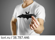 A man in a white t-shirt holds a black silhouette of a bat. Close up. Стоковое фото, фотограф Плотников Дмитрий / Фотобанк Лори