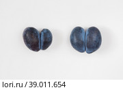 Trendy ugly food concept. Two purple plums on a white background. Стоковое фото, фотограф Марина Багрова / Фотобанк Лори