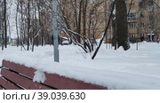 Мужчина прогуливается по городскому парку после сильного снегопада или снежной бури. Заснеженный сквер во дворе жилого многоквартирного дома.  Зима в большом городе. A man walks through a city park after a heavy snowfall or a snowstorm. A snow-covered square in the courtyard of a residential apartment building. Winter in the big city. Стоковое видео, видеограф Ирина / Фотобанк Лори