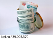 Концепт сбережения денег. Деньги в банке. Доллары США и российские рубли в стеклянной банке. (2018 год). Редакционное фото, фотограф Александр Тарасенков / Фотобанк Лори