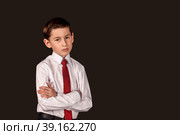 Bossy displeased and discontent serious boy in white shirt and tie on black isolated background. Angry child boss with emotions discontent, looking at camera. Contempt, disrespect concept. Copy space. Стоковое фото, фотограф Aleksandr Golubev / Фотобанк Лори