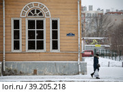 Город Калуга, улица Ленина, 70. Фрагмент фасада с окном главного дома усадьбы XVIII века -  дома Польман. Мимо по улице идет женщина. В глубине двора видна желтая табличка с надписью "Частная территория" (2021 год). Редакционное фото, фотограф Наталья Николаева / Фотобанк Лори