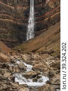 Hengifoss waterfall in East Iceland. Hengifoss is the third highest waterfall in Iceland and is surrounded by basaltic strata with red layers of clay between the basaltic layers (2020 год). Стоковое фото, фотограф Igor Tichonow / Фотобанк Лори