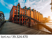 Arch bridge over canals in the Speicherstadt of Hamburg. Warm evening sun light on red brick building (2018 год). Стоковое фото, фотограф Igor Tichonow / Фотобанк Лори