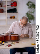 Old male repairman repairing musical instruments at workshop. Стоковое фото, фотограф Elnur / Фотобанк Лори