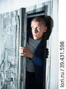 Young man tries to open the door to the quest room, stylized as a secret hideout. Стоковое фото, фотограф Яков Филимонов / Фотобанк Лори