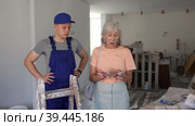Senior woman paying wage to teenage boy assistant in construction site. Стоковое видео, видеограф Яков Филимонов / Фотобанк Лори