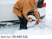 A man digs out a stalled car in the snow with a car shovel. Transport in winter got stuck in a snowdrift after a snowfall, sat on the bottom. First aid, tow truck, winter tires spikes and all-season. Стоковое фото, фотограф Ольга Симонова / Фотобанк Лори