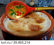 Хохломская ложка и глиняный горшок с пшенной кашей из печи. Каша на молоке с маслом. Крупный план. Натуральная, здоровая пища. Традиционная русская еда. (2019) Редакционное фото, фотограф Сергей Елизарьев / Фотобанк Лори