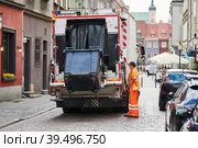 garbage and waste removal services. Worker loading waste bin into truck at city. Стоковое фото, фотограф Дмитрий Калиновский / Фотобанк Лори
