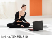 Woman universal yoga trainer greets pupils at the laptop before doing an online workout. Стоковое фото, фотограф Сергей Чайко / Фотобанк Лори