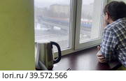 A man comes to the window and looks at the city landscape. Household sketch. Стоковое видео, видеограф Ярославский Максим / Фотобанк Лори