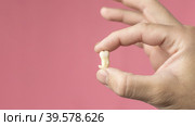 Close-up: a man's hand holds a removed wisdom tooth or a third molar on a pink background,copy space. Banner. Стоковое фото, фотограф Регина Ерофеева / Фотобанк Лори