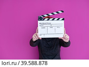 woman holding movie clapper isolated on pink background. Стоковое фото, фотограф Benis Arapovic / PantherMedia / Фотобанк Лори