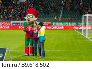 Девушки-болельщицы московского клуба "Локомотив" фотографируются на футбольном поле с куклой-символом клуба "Локомотив" (2019 год). Редакционное фото, фотограф Pukhov K / Фотобанк Лори