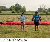Инструктаж пассажира мотопараплана перед взлётом. Instructing of a paramotor passenger before takeoff. (2022 год). Редакционное фото, фотограф Евгений Романов / Фотобанк Лори