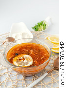 Мясная Солянка. сборная солянка. порция острого красного мясного супа с помидорами, копченостями сосисками и оливками с лимоном на светлом фоне. Стоковое фото, фотограф Оксана Медведева / Фотобанк Лори