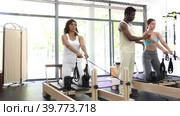 African american man helps women to exercise on the simulators during pilates class. Стоковое видео, видеограф Яков Филимонов / Фотобанк Лори