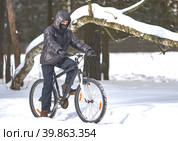 Winter sports. Cycling trips. A young man in black clothes rides a bicycle. Стоковое фото, фотограф Кутина Татьяна / Фотобанк Лори