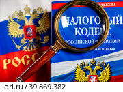 Налоговый кодекс под увеличительным стеклом лежат на столе (2023 год). Редакционное фото, фотограф Николай Винокуров / Фотобанк Лори