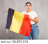 Sad young woman holding Belgium flag against unicoloured background. Стоковое фото, фотограф Яков Филимонов / Фотобанк Лори
