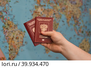Travelling with a Russian passport around the world: two Russian sports are holding in their hands against the backdrop of the map of the world. Путешествие с паспортом Российской Федерации : в руке держит два росссийских загранпаспорта на фоне карты мира. Стоковое фото, фотограф Тамара Сахарова / Фотобанк Лори