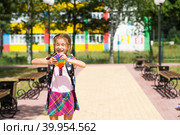Little girl with a backpack and in a school uniform in the school yard plays pop it toy. Back to school, September 1. The pupil relaxes after lessons. Primary education, elementary class for student. Стоковое фото, фотограф Ольга Симонова / Фотобанк Лори