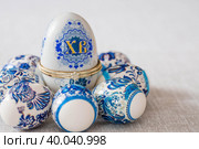 Большая коробка для яиц с надписью XB и пасхальные яйца в традиционном русском стиле на льняной скатерти на столе. Гжель. Концепция светлого праздника Пасхи. (2023 год). Редакционное фото, фотограф Photojuli / Фотобанк Лори