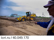 South Kazakhstan - April, 26 2012: Development of West Europe-West China road. Groundworks with bulldozer. Worker with signal flag right. Редакционное фото, фотограф Alexey Rezvykh / Фотобанк Лори