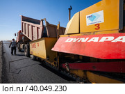 Kyzylorda province, Kazakhstan, April 29, 2012: Construction of West Europe-West China new highway. Dump truck unloads hot asphalt in Dynapac road machine hopper. Стоковое фото, фотограф Alexey Rezvykh / Фотобанк Лори