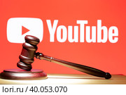 Syktyvkar, Komi, Russia,December 24, 2022,YouTube . A hammer on the table against the background of the YouTube logo. The concept of the trial. Редакционное фото, фотограф Александр Поташев / Фотобанк Лори