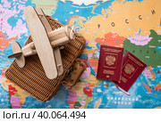 Туризм. Модель старинного самолета, чемодан и российский паспорт на фоне карты мира. Концепция путешествий, приключений и открытий. (2023 год). Стоковое фото, фотограф Photojuli / Фотобанк Лори