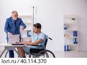 Young male employee in wheel-chair feeling bad at workplace. Стоковое фото, фотограф Elnur / Фотобанк Лори