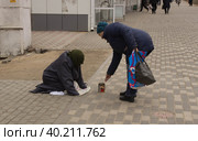 Акт милосердия. Прохожая женщина подает милостыню нищей. Липецк. (2023 год). Стоковое фото, фотограф Евгений Будюкин / Фотобанк Лори
